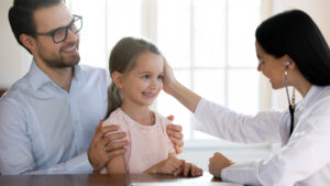Nena acompañada de papá recibiendo atención médica gracias a su seguro