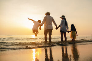 Familia feliz saltando juntos en la playa de vacaciones porque saben que los seguros los protegen